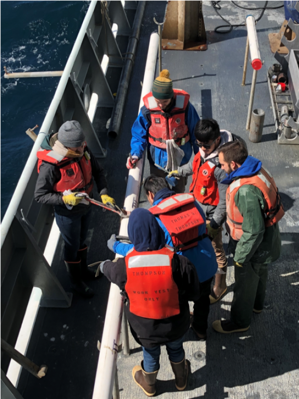 Day watch researchers Jose Córdova, Tanner Eischen, and Ruby Schaufler from Texas A&M University, along Aaron Watters and Mark Yu from Rutgers Universtiy, and Gregorio Diaz Torres from Argentina cutting a sediment core on the deck after recovery. (Photo courtesy of James Wright)