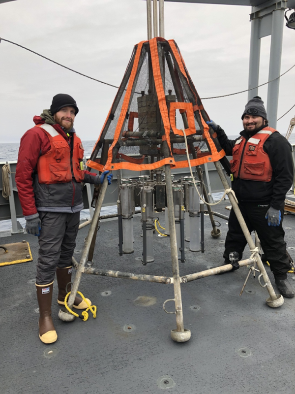 Texas A&M graduate student Richard Rosas (right) and Tim Shamus from Rutgers University (left), standing next to the multi-corer, which has clear plastic tubes attached to it. (Photo courtesy of James Wright.)