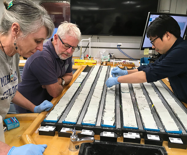 At the sampling table: Ingrid Hendy, sedimentologist, University of Michigan; Christopher Hollis, observer/micropaleontologist, GNS Science, New Zealand; and Wei Yuan, paleomagnetist, Tongji University, China. (Photo credit: Lindy Newman and IODP.) 