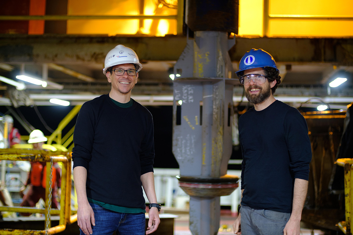 Dr. Patrick Fulton (Right, Texas A&M Geology and Geophysics) and Dr. Demian Saffer (Left, Penn State University) stand in front of one of two sub-seafloor observatories before it is installed beneath the sea, while on board the JOIDES Resolution for IODP Expedition 375. (Credit: Patrick Fulton / IODP)