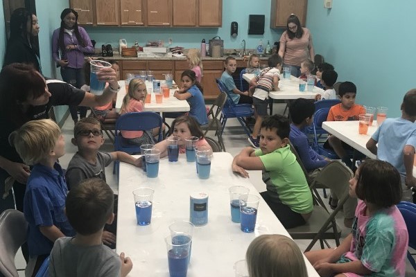 Dr. Chrissy Wiederwohl teaching students how adding salt to water changes density (Photo courtesy of the Children’s Museum of the Brazos Valley.)