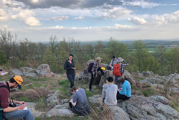 Dr. Kenderes pictured teaching an igneous petrology class at Knob Lick, Missouri. Knob Lick is part of the rim of a Precambrian age caldera in south-eastern Missouri. (Photo courtesy of Kenderes.)