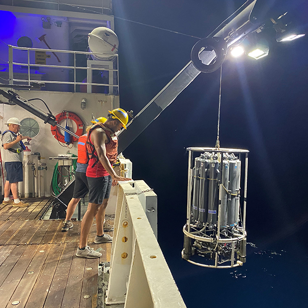 Students helping lower the CTD rosette into the water during the night shift. Image credit: Gabriel Lucio.