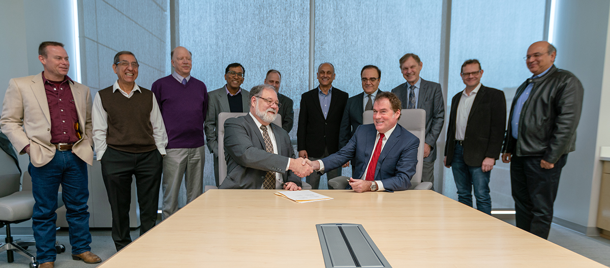 Mark A. Barteau, vice president for research at Texas A&M University, shakes hands with Michael M. Watkins, director of the Jet Propulsion Laboratory, after signing a three-year strategic partnership between the institutions. Standing are representatives from the laboratory and faculty members from Texas A&M’s colleges of engineering, science and geosciences. (Image: College of Engineering)