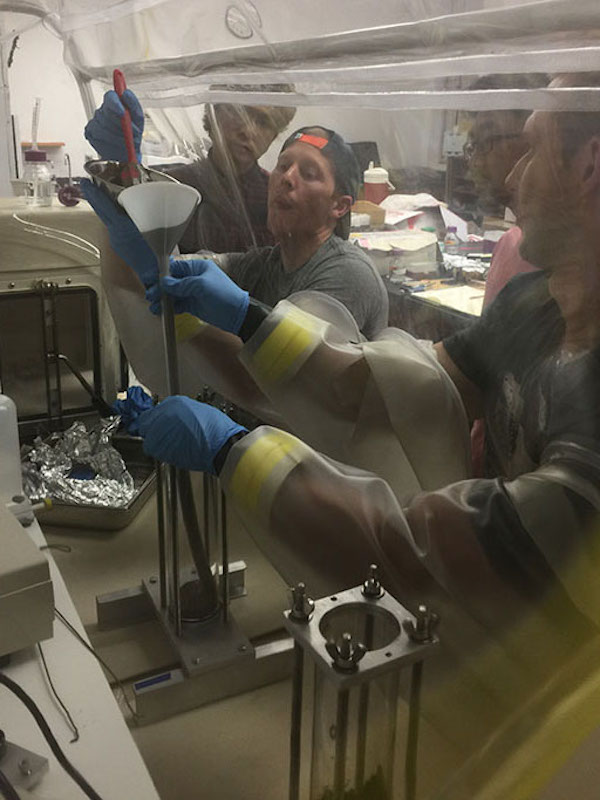 Graduate Teaching Assitant (TA), Tanner Mills, works with undergraduate students to funnel sediments in an anaerobic chamber. (Photo courtesy of Dr. Julia Reece)