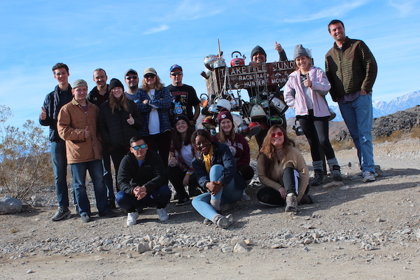 Group photo of GEOL 330 students, TA, and instructor at Teakettle Junction in Death Valley National Park, CA. (Photo courtesy of Dr. Brian Balta.)