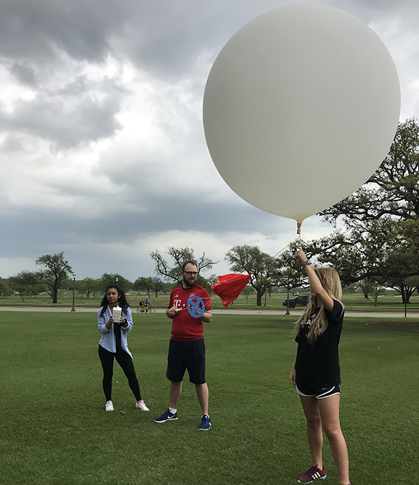 Sherman assisting with a weather balloon launch, holding the radiosonde, which is the instrument that sends back all of the data.