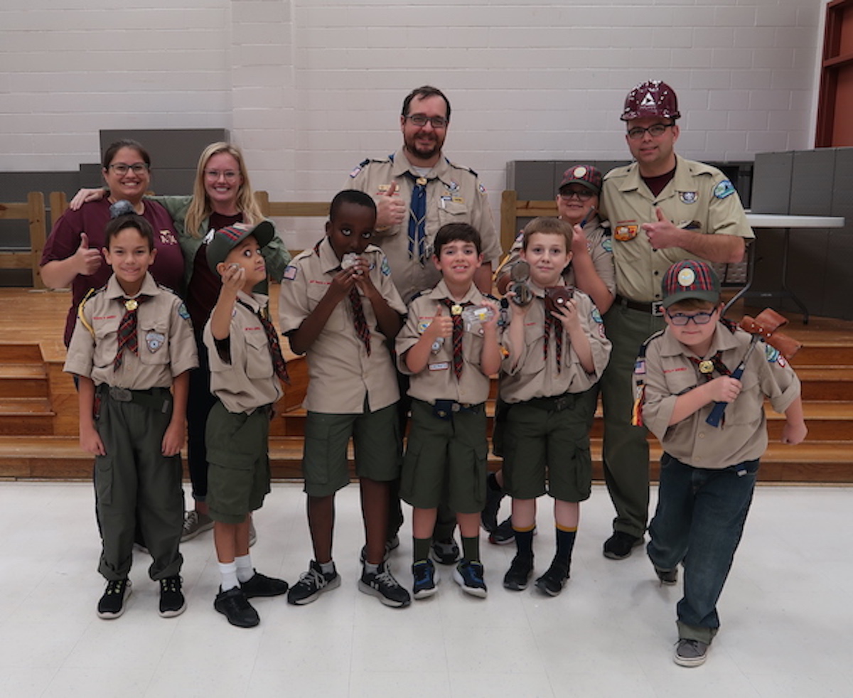 Michelle Chrpa and Ali Snell (top left) with the Webelos group of Scouts Pack 62. Each Webelo member is displaying their favorite geology related item from the outreach event. (Photo courtesy of Andrew Armstrong.)
