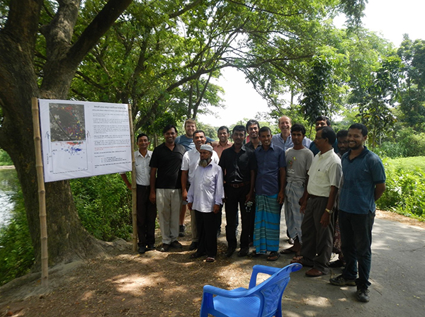Five of the study’s authors, including Texas A&M’s Dr. Peter Knappett (third from left), near the village of Baylakandi, Bangladesh in 2013. The sign on the left helped inform people about where safe wells were located. (Photo courtesy of Knappett.)