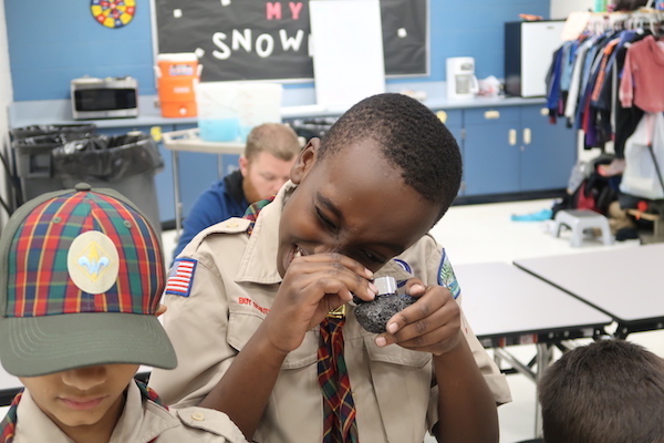 A Webelo uses a hand lens to take a closer look at an igneous rock sample. (Photo courtesy of Andrew Armstrong.)